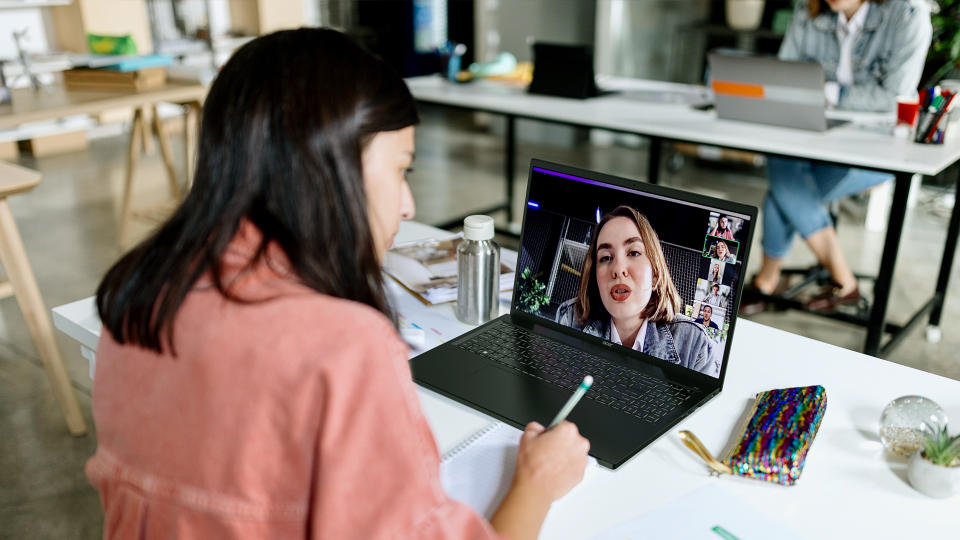 A person sits at a desk and makes a video call with another person on an Acer Swift Edge 16. Open office workspace.